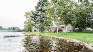 Un quartier résidentiel avec une maison située près d’un plan d’eau, entourée d’arbres et d’une pelouse verdoyante.