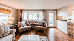 Un salon chaleureux avec deux fauteuils, une petite table et une vue sur l’extérieur grâce à de grandes fenêtres.
