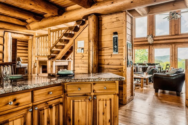 A log cabin interior with a kitchen, dining area, and a staircase.