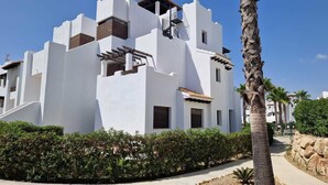 Un bâtiment moderne de couleur blanche, doté de balcons, avec un palmier au premier plan.