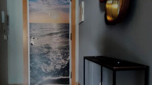Un couloir avec une porte donnant sur une pièce, une console et des appliques murales.