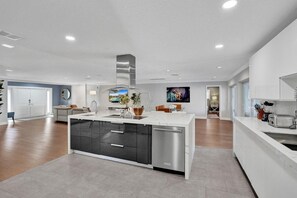 A modern kitchen with a central island, built-in appliances, and a dining area with a view.
