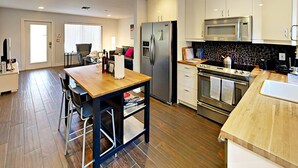 Una cocina moderna con electrodomésticos de acero inoxidable, una mesa de comedor de madera y un salpicadero de piedra.