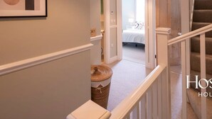 A hallway leading to a bedroom with a bed, a hanging light fixture, and a staircase. - Marlow s Hidden Gem (Marlow)