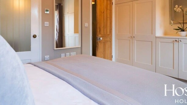 A bedroom with a bed, a wooden door, and a mirror. - Marlow s Hidden Gem (Marlow)