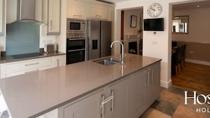 A modern kitchen with stainless steel appliances, a large island, and a dining area visible through an open doorway. - Marlow s Hidden Gem (Marlow)
