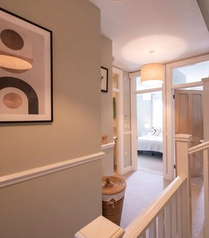 A hallway leading to a bedroom with a bed, a hanging light fixture, and a staircase. - Marlow s Hidden Gem (Marlow)