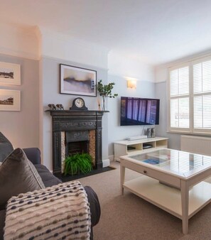 A living room with a fireplace, a TV, and a large window.