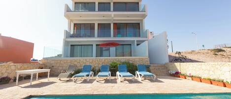A modern two-story building with a swimming pool in front.