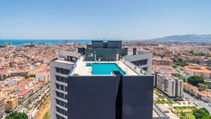 Un edificio alto con piscina en la azotea, con vistas a la ciudad y al mar.