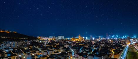 Une vue nocturne d’une ville, avec des bâtiments illuminés et un ciel étoilé.