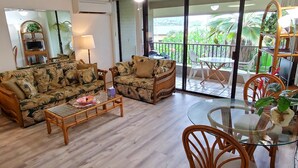 A living room with a sofa, a coffee table, and a dining area with chairs and a table. - Condo in the center of Kona, 2-unit AC, Washer/Dryer, Full Kitchen, Free Parking (Kailua-Kona)