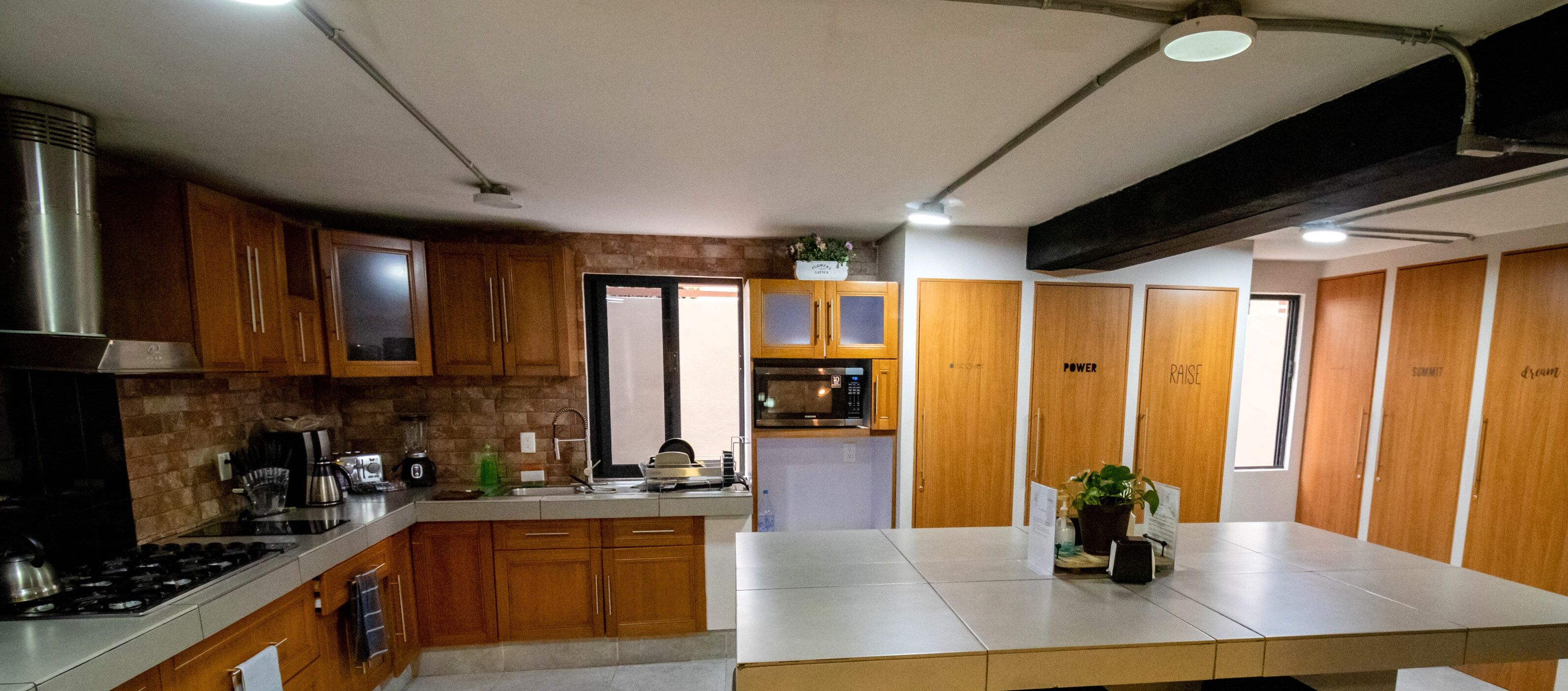 A modern kitchen with wooden cabinets, a central island, and a built-in oven.