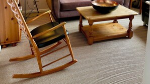 Un salon comprenant un canapé, une table basse, un fauteuil à bascule et un lampadaire.