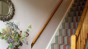 Un escalier avec une rampe en bois et une moquette à rayures multicolores.