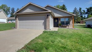 A single-story house with a garage, a front porch, and a small patio. - Laura’s Simply Charming Home on Harrison (Quincy)