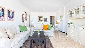 A modern living room with a white sofa, a coffee table, and a cabinet with glass doors. - Maritimo Rey | Beach Front Apartment in Fuengirola (Fuengirola)