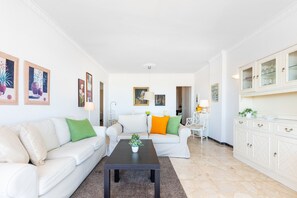 Una sala de estar moderna con un sofá blanco, una mesa de centro y un mueble con puertas de vidrio.