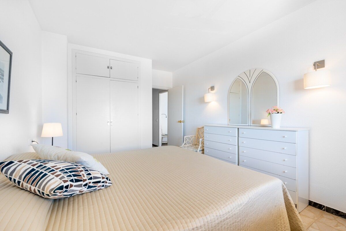 Ein Schlafzimmer mit einem Bett, einem Schminktisch, einem Spiegel und einer Lampe.