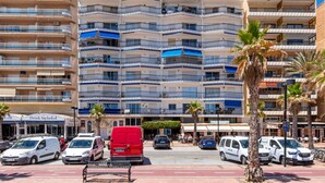 A multi-story hotel with balconies, a parking area, and palm trees. - Maritimo Rey | Beach Front Apartment in Fuengirola (Fuengirola)