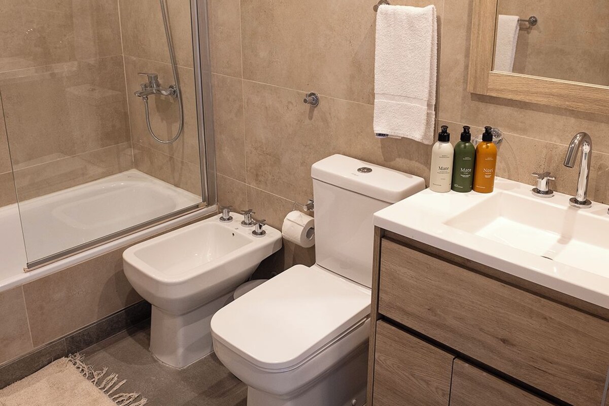 A modern bathroom with a bathtub, bidet, toilet, and sink.