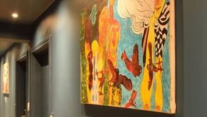 Un couloir orné d’un grand tableau abstrait au mur.