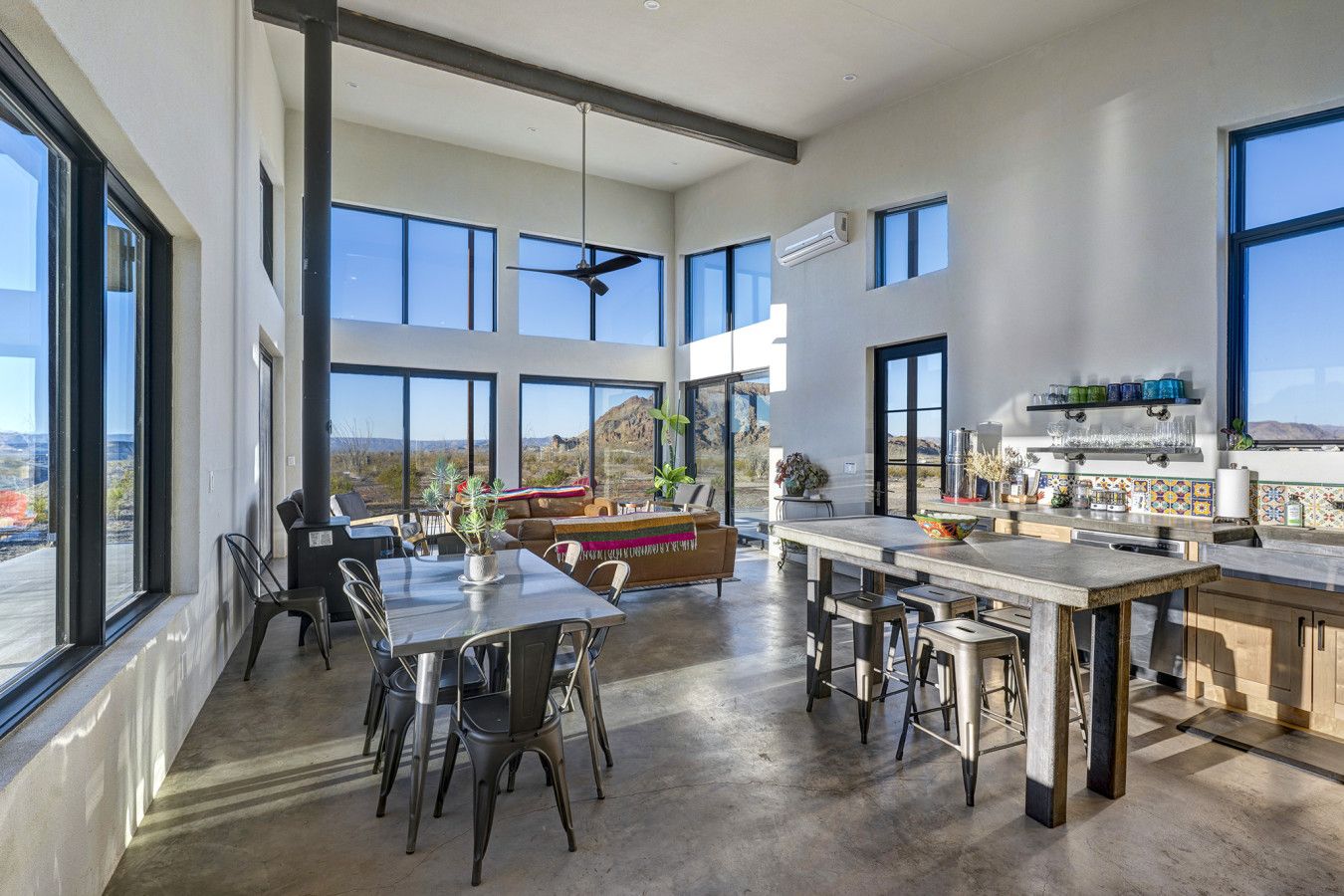 A spacious kitchen with large windows, a dining area, and a living space with a view of the desert.