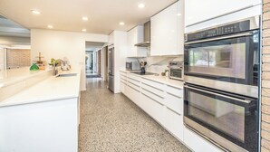Una cucina moderna con mobili bianchi, elettrodomestici in acciaio inossidabile e un piano di lavoro in granito.