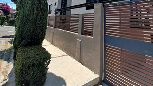 Un bâtiment moderne à deux étages, doté d’une façade grise, de grandes fenêtres et d’une entrée sécurisée par un portail.