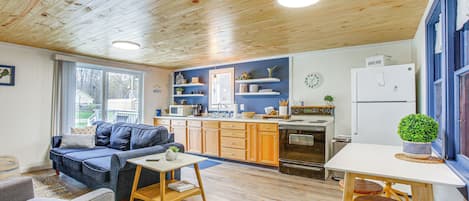 Una sala de estar acogedora con un sofá, una mesa de centro y un comedor con una mesa y taburetes.