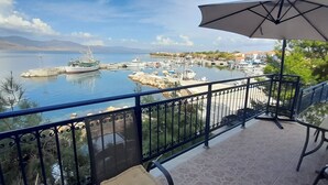 Een balkon met uitzicht op een jachthaven, een tafel met stoelen en een parasol.