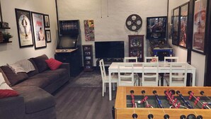 Una sala de estar acogedora con un sofá, una mesa de fútbol de mesa, un televisor y una chimenea.