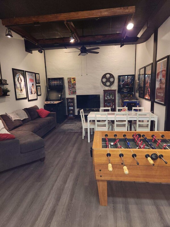 Una sala de estar acogedora con un sofá, una mesa de fútbol de mesa, un televisor y una chimenea.