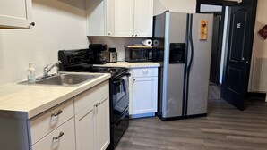 Una cocina moderna con armarios blancos, un refrigerador de acero inoxidable, un microondas, una estufa y un lavamanos.