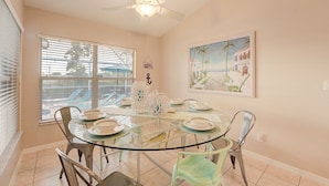 A dining area with a glass table, metal chairs, and a ceiling fan.