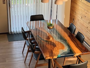 A dining table with a glass top and wooden frame, surrounded by black chairs. - West Glacier Sleeps 4 On Golf Course W/ Golf Cart (Flathead County)