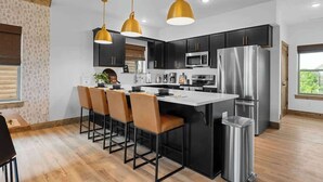 A modern kitchen with black cabinets, stainless steel appliances, and a central island with bar stools. - Sauna·Lake View·Hot Tub·Pickleball·Pools·Fire Pit (Branson)