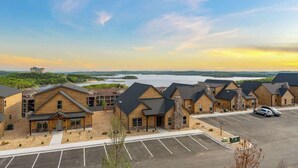 A row of log cabin-style buildings with a parking lot in front, overlooking a body of water. - Sauna·Lake View·Hot Tub·Pickleball·Pools·Fire Pit (Branson)