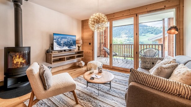 A cozy living room with a fireplace, a television, and a view of a deck and mountains. - Opale - Cozy apartment with terrace in Megève (Megeve)