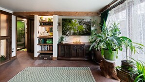 Een gezellige kamer met een houten kast, een grote televisie en diverse potplanten.
