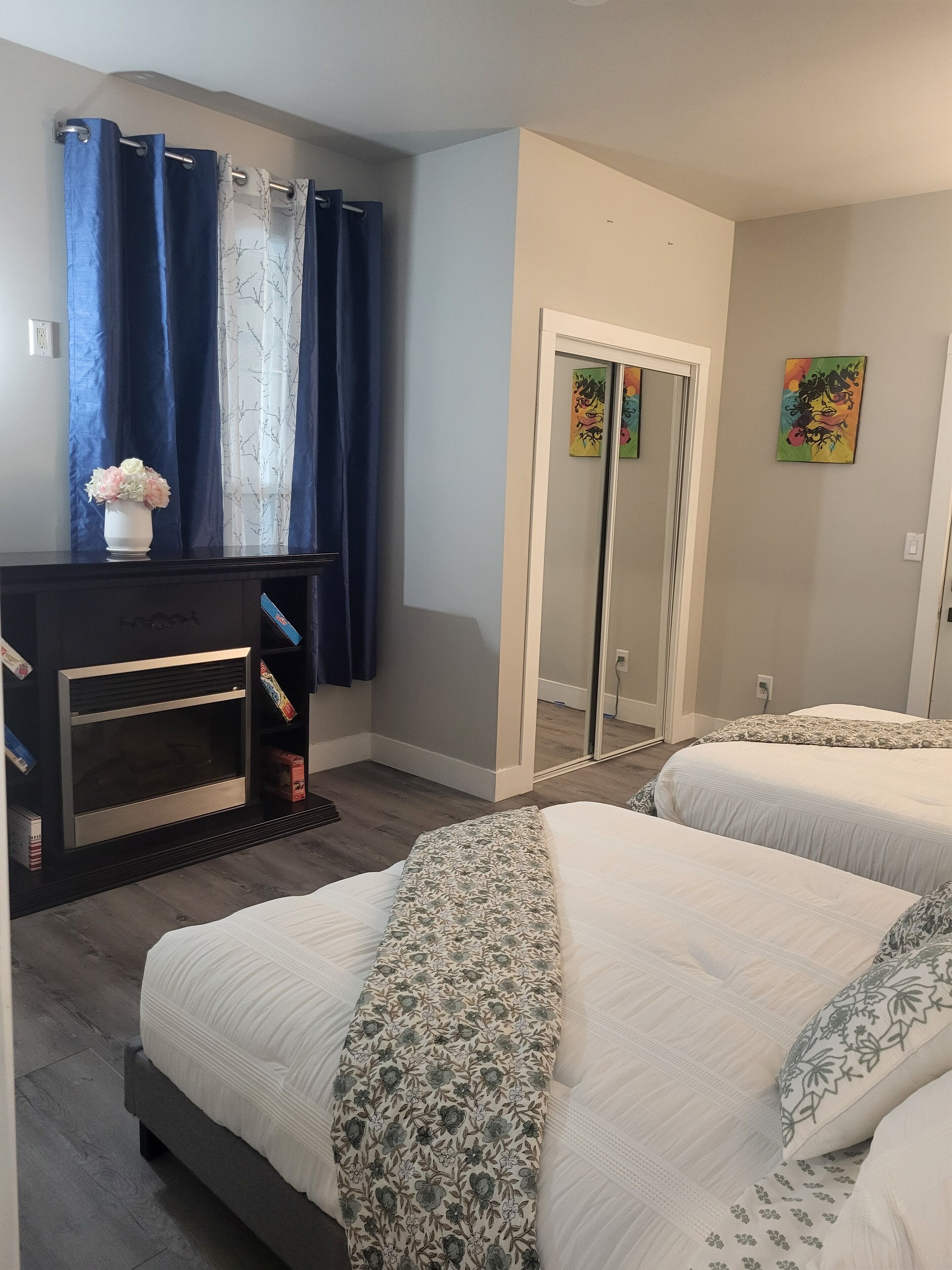 A bedroom with two beds, a dresser, a mirror, and a door leading to a bathroom.