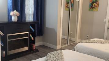 A bedroom with two beds, a dresser, a mirror, and a door leading to a bathroom.