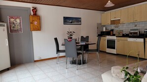 A compact living space with a dining area, kitchenette, and a sofa. - Appartement au Calme (Bonnevaux)