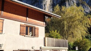 A two-story building with wooden shutters and a balcony, set against a mountainous backdrop. - Appartement au Calme (Bonnevaux)