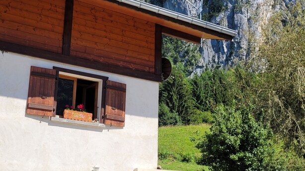 A two-story building with wooden shutters and a balcony, set against a mountainous backdrop. - Appartement au Calme (Bonnevaux)