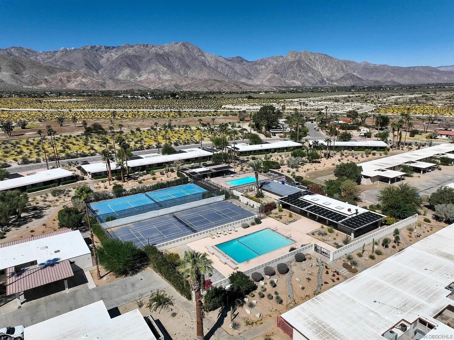 A hotel with multiple swimming pools, a desert landscape, and mountains in the background.