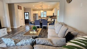 A modern living room with a sofa, coffee table, and dining area. - Modern Retreat in Sherman TX (Sherman)