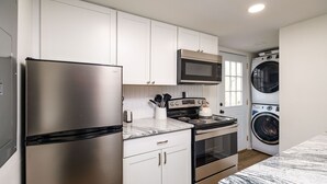 A modern kitchen with stainless steel appliances, white cabinetry, a microwave, a stove, and a washing machine. - Private, Hot tub, Firepit, Bocce Ball, Horse Shoes, Outdoor Ping Pong Table (Shenandoah)