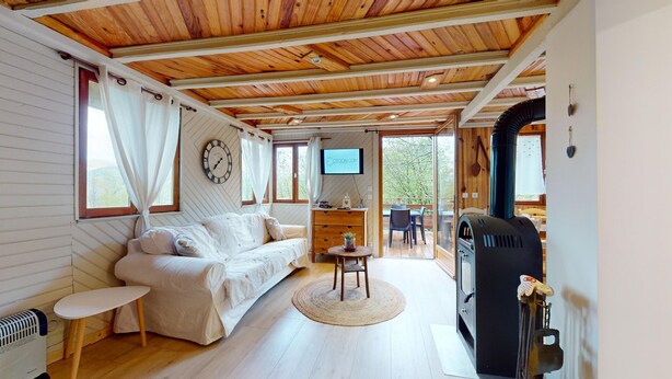 Une pièce chaleureuse avec un plafond en bois, un canapé blanc, un téléviseur et une cheminée.