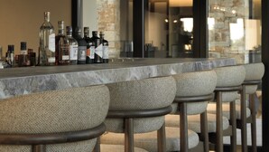 A bar area with a marble countertop and multiple stools. - The Key  (Naxos)